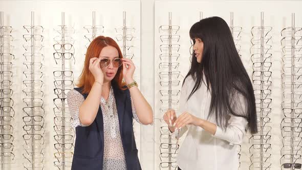 Two Girlfriends Choose Optician Sunglasses Holiday.