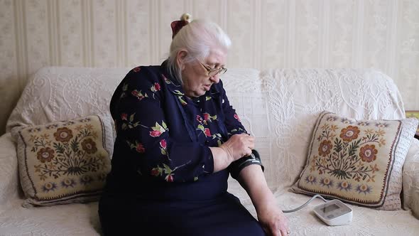 An elderly woman measures the pressure with a special device