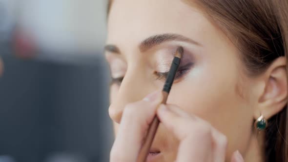 Makeup Artist Blending Eyeshadows To Model in Beauty Salon