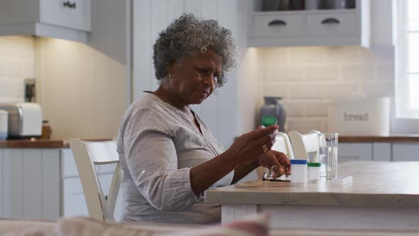 Senior african american woman looking at empty medication container while sitting at home