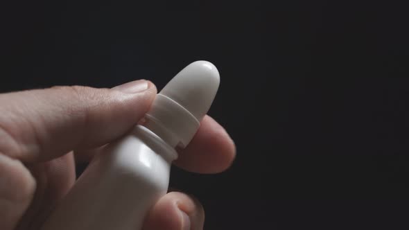 Close-up of a Person Holding a Nose Drop on a Dark Background