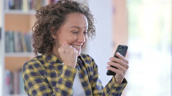 Portrait of Mixed Race Woman Celebrating on Smartphone