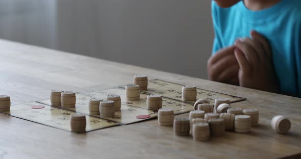 Children play Russian loto on the table. Game of kegs with numbers.