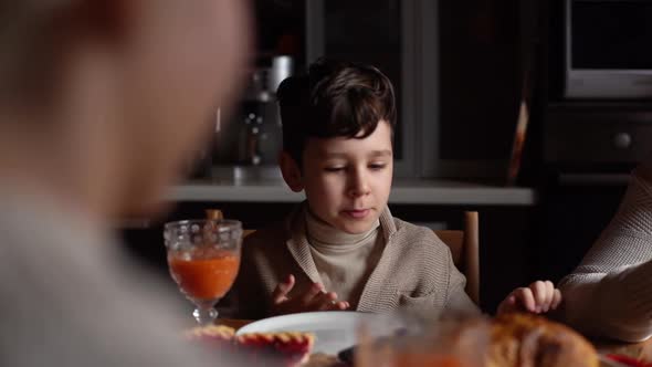 Tracking Shot of Happy Little Child Boy Talking to Parents at Festive Christmas Dinner Table During