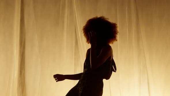 Professional Dancer Performing Against Stage Curtain with Warm Backlit