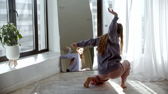 Young Pretty Woman Stands Up in Front of a Mirror and Starts Dancing