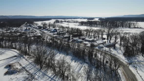 Aerial view of frozen river in snow covered valley with island with trees. Bright blue sky. alt