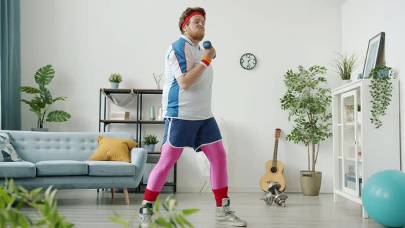 Slow Motion of Funny Fat Guy in Bright Clothing Exercising with Dumbbell and Eating Banana Looking