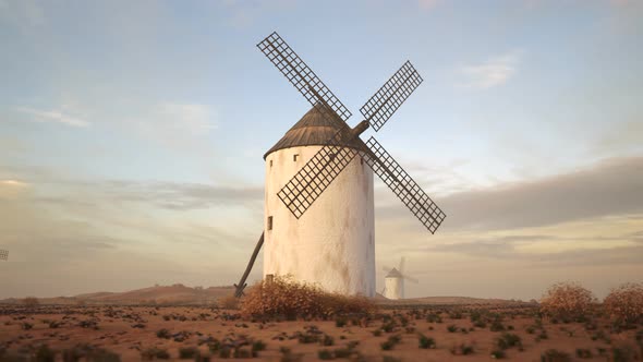 Closeup shot of a vintage Spanish windmill's wings rotating slowly at sunset. 4K