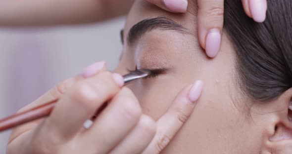 Make Up Artist Lining Eyes of Asian Girl with Brush and Eyeshadows, Close Up