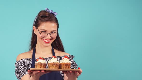 Young Woman Pastry Chef with Cupcakes in Hand Smiling at Camera