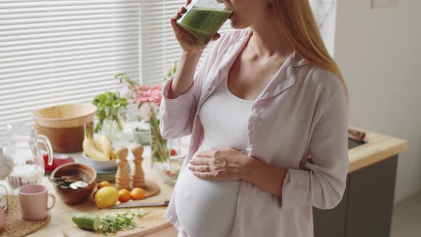 Pregnant Woman Stroking Belly and Drinking Smoothie