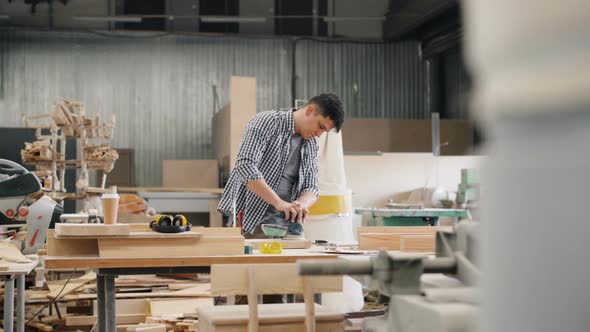 Factory Worker Polishing Wood with Electric Machine in Spacious Workshop