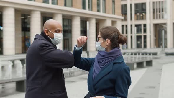 Diverse Colleagues Wearing Face Protective Masks Bumping Elbows, Greeting Each Other Outdoors