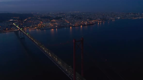 Night Aerial Panorama of Urban City Center of Lisbon in Lights with Ponte 25 De Abril Red Bridge