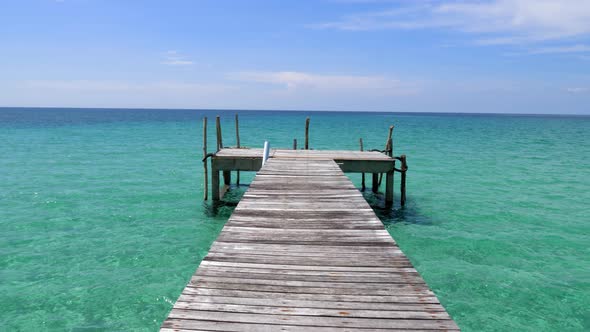 A T shape pier facing the open ocean, blue skies, green ocean