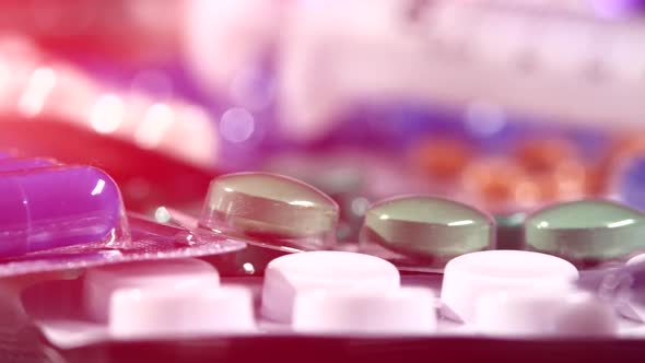 Some Different Contraceptive Pills and Two Syringes, Rotation, Reflection, Close Up, Pink Light