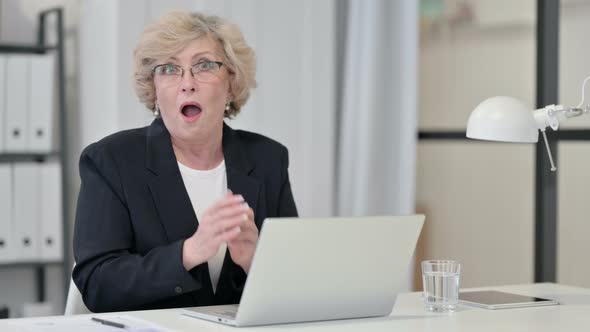 Shocked Old Businesswoman with Laptop Looking at Camera