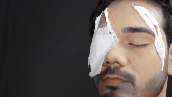 Make up artist applying white prosthetic insert on man's face to make a Halloween mask