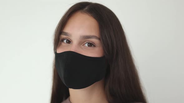 Portrait Young Brunette Female in Black Protective Medical Mask Looking Camera