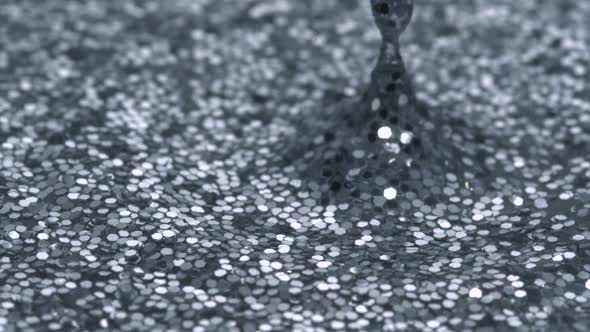 Water drop making ripple on water filled with glitter, Slow Motion