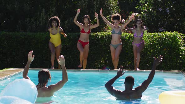 Diverse group of friends having fun jumping into a swimming pool