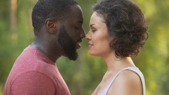 Black male and white female delicately touch noses and smile happily afterwards