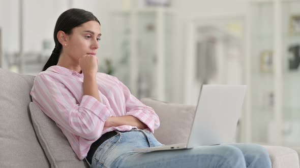 Pensive Young Latin Woman Thinking and Working on Laptop at Home 
