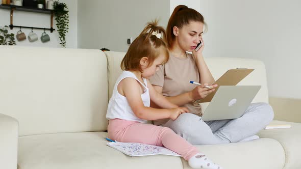 Mother Working From Home Having a Work Video Call Phone Call While Her Child Distracts and Drawing