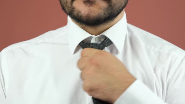 A Man with a Beard and a White Shirt is Straightening His Tie