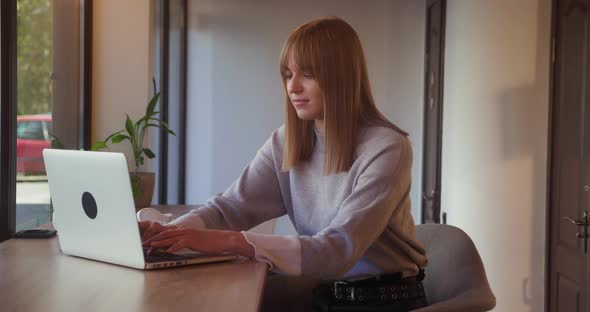 Blonde Freelancer Working on Laptop in Cafe