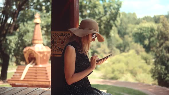 Woman In Hat Using Cellphone Outdoor. Female Portrait Picture Via Mobile App. Girl Taking Photo.