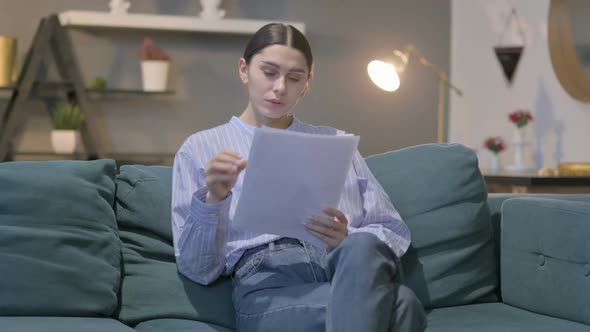 Hispanic Woman Reacting to Loss on Documents, Sofa