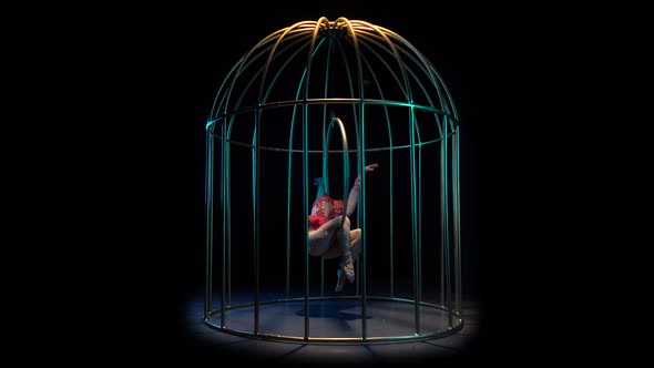 Actress in a Red Costume on a Gymnastic Hoop Performs Tricks in a Cage 