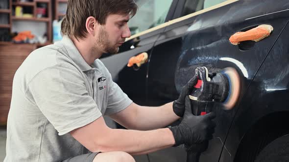 Car Mechanic Worker Hands Polishing a Car Side with a Orbital Polishing Machine