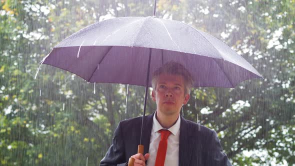 Businessman Sheltering Underneath an Umbrella in the Rain