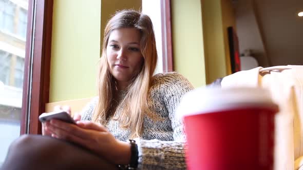 Beautiful woman in a cafe texting on the phone