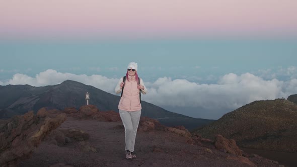 Slow Motion Happy Girl Face in Pink Sunset Light on Mountain Above Purple Clouds