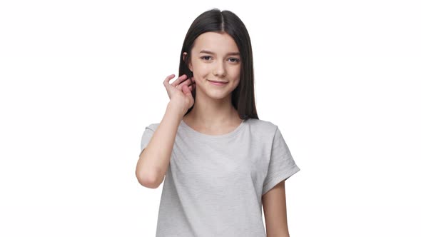 Portrait of Beautiful Teen Girl in Basic Tshirt Smiling at Camera and Touching Her Long Dark Hair