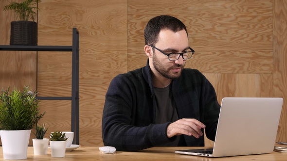 Hipster man with laptop talking to himself.