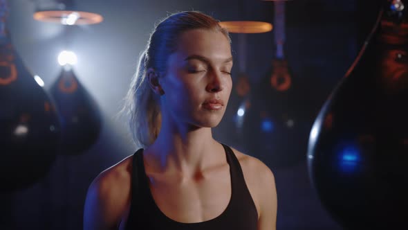 Portrait of Beautiful Youngsport Woman Boxer Turning Face to Camera with Serious Look at Dark Ring