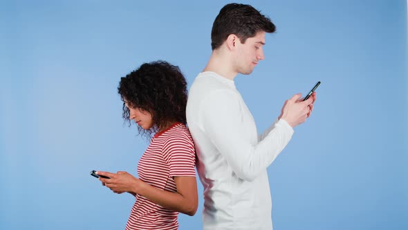 Interracial Couple Stand with Their Backs to Each Other and Print Messages or Surf Internet From