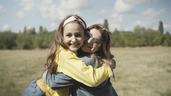 Camera Approaches To Two Happy Joyful Young Hippie Women Hugging Outdoors Smiling Camera