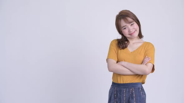 Profile View of Happy Young Beautiful Asian Woman Smiling with Arms Crossed