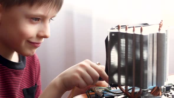 Caucasian preschooler repairs a computer with his own hands.