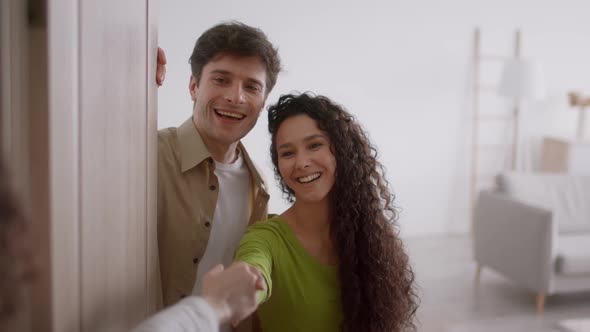 Cheerful Couple Opening Door Shaking Hands Standing In Doorway Indoor