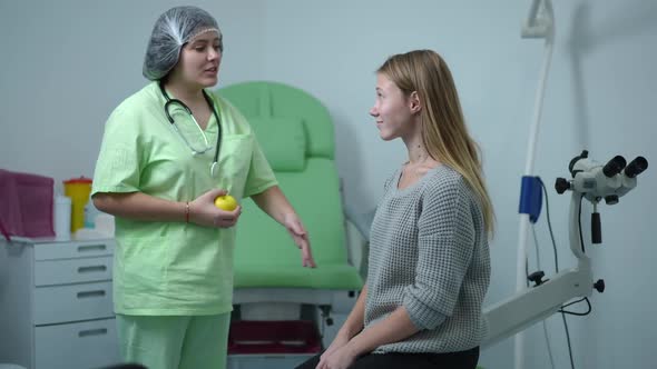 Positive Caucasian Gynecologist Endorsing Teenage Patient Sitting on Gynecological Chair in Hospital