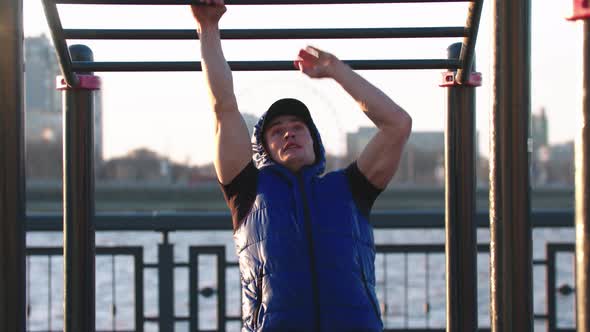 Handsome Sportive Man Training His Hands on the Bars Outdoors