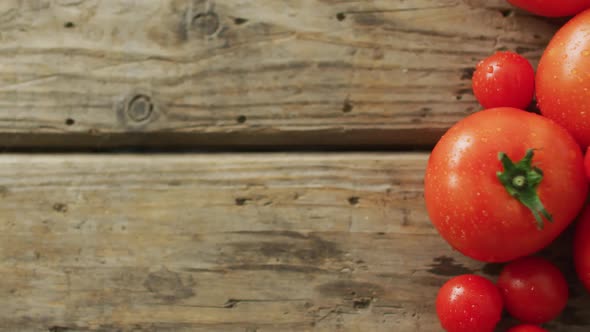 Video of fresh tomatoes and cherry tomatoes with copy space over wooden background