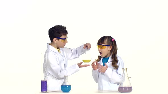 Two Cute Children in Protactive Glasses and Uniform Making Chemical Experiments on White Background